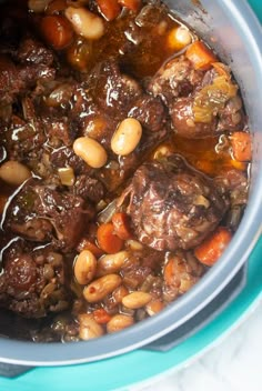 a pot filled with meat and beans on top of a table