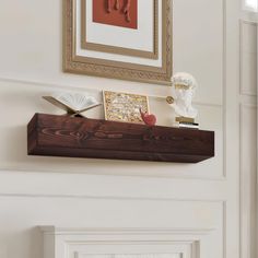 a wooden shelf with books and pictures on it in front of a framed photograph above the fireplace