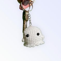 a hand holding a keychain with a stuffed animal on it's side