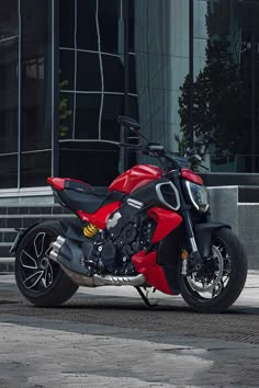 a red and black motorcycle parked in front of a building