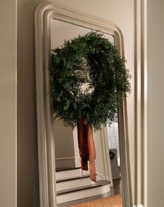 a wreath is hanging on the wall in front of a mirror