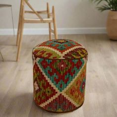 a colorful ottoman sitting on top of a hard wood floor next to a wooden chair