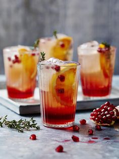 three glasses filled with drinks and garnished with pomegranates on a tray