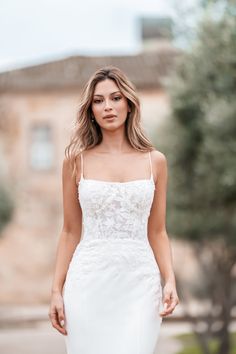 a woman in a white wedding dress is walking down the street with her hand on her hip