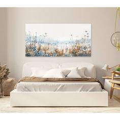 a white bed sitting in a bedroom next to a painting on the wall above it