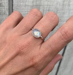 A beautiful luminescent white oval moonstone has been horizontally set in sterling silver with a handmade ring band from sterling silver half dome wire. The white moonstone changes colors when the light hits it going from a crisp white to having hues of blue, orange, or pink. The stone is 10mm x 8mm in size.  Made to order, please specify size when ordering! Each moonstone will vary in color, hues, and inner texture. If you would like to see the available moonstones, just ask! Moonstone is also Oval Moonstone Jewelry For Everyday, Everyday Oval Moonstone Jewelry, Minimalist White Moonstone Ring In Sterling Silver, Modern Oval Moonstone Jewelry, Adjustable Minimalist Moonstone Ring In Sterling Silver, Minimalist Adjustable Sterling Silver Moonstone Ring, Modern Adjustable Oval Moonstone Ring, White Moonstone Opal Ring In Oval Cabochon Shape, Modern Oval Moonstone Promise Ring