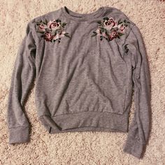 Grey Crewneck !! Has Flowers Embroidered On Each Side And Bought In Europe. Never Worn Before And In Great Condition ! Casual Crew Neck Top With Embroidered Hem, Spring Long Sleeve Sweatshirt With Floral Embroidery, Spring Long Sleeve Tops With Embroidered Graphics, Spring Floral Embroidery Long Sleeve Sweatshirt, Spring Floral Embroidered Long Sleeve Sweatshirt, Cute Floral Embroidered Long Sleeve Tops, Cute Floral Embroidery Fall Tops, Spring Pink Sweatshirt With Embroidered Graphics, Spring Floral Embroidered Crew Neck Sweatshirt