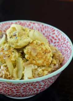 a red and white bowl filled with food on top of a table