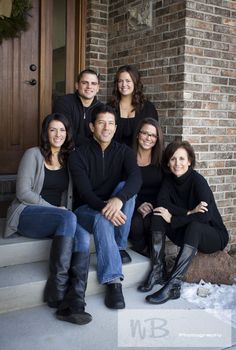 a group of people sitting on the steps in front of a door with their arms around each other