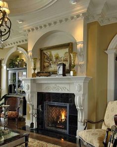 a living room filled with furniture and a fire place under a chandelier in front of a fireplace