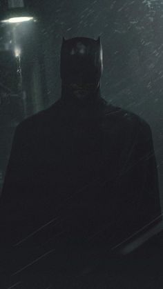 the dark knight is standing in the snow at night with his head turned to the side