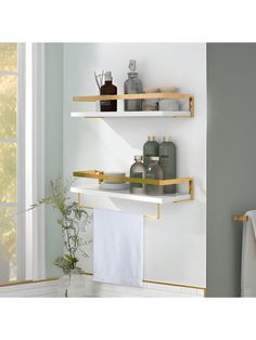 two shelves with towels, soap and other items on them in a white room next to a window