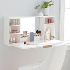 a white chair sitting in front of a mirror on top of a counter next to a shelf