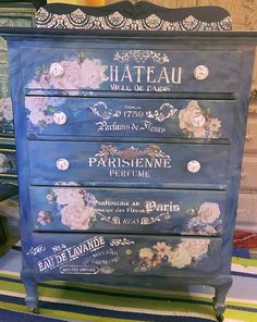 a blue dresser with flowers painted on the front and drawers in french scripturals