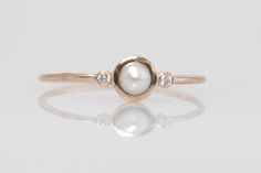 Mesmerizing++pearl+and+diamond+engagement+ring,+delicate+pearl+wedding+ring,+three+stone+ring.    This+ring+is+handcrafted+in+14k+yellow+gold.+    In+the+back+of+the+ring-+tiny+heart-++symbol+of+Love.+      Center+stone:  *+natural,+freshwater+pearl  *+3mm-3.5mm    Side+stones:  *natural,+Earth+m... Non Diamond Engagement Rings Gemstone, Engagement Rings Pearl, Pearl And Diamond Engagement Ring, Engagement Ring Delicate, Pearl Diamond Ring, Pearl Wedding Ring, Natural Pearl Ring, White Pearl Ring, Jewelry Repurposed