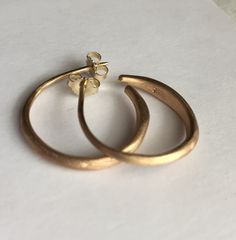 "14k gold hoop earrings. Fantastic weight and feel to these hoop earrings where I forge and shape metal wire into a tapered hoop giving these a rustic handmade look and feel. Matt finish with post and ear nuts. Tapers from about 3mm (1/8\")down to 1mm, going from thick to thinner. No 2 pair are going to be exactly the same because of the way these are made. If you like a certain pair you can ask me to try to get them as close to those as I can. Sizes-3/4\" or 1\" across 14K Available in Yellow g Minimalist Small Hoop Earrings In Recycled Gold, Modern Small Hoop Earrings In Recycled Gold, Handmade 14k Gold Minimalist Huggie Earrings, Handmade Minimalist 14k Gold Huggie Earrings, Minimalist Hammered Hoop Earrings For Anniversary, Minimalist Recycled Gold Hoop Earrings, Handmade Minimalist Yellow Gold Huggie Earrings, Minimalist Handmade Yellow Gold Huggie Earrings, Modern Small Hoop Earrings Hand Forged