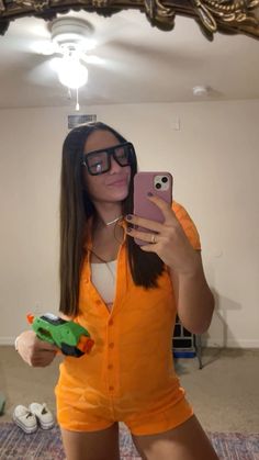 a woman taking a selfie in front of a mirror wearing an orange romper