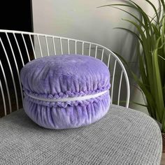 a purple pillow sitting on top of a white chair next to a potted plant