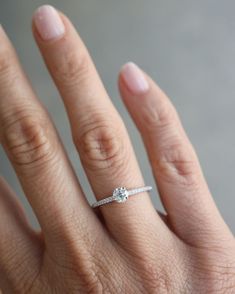 a woman's hand with a diamond ring on her left hand and the other hand holding an engagement ring