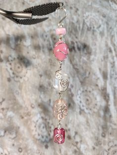 a pink and white beaded necklace hanging from a hook