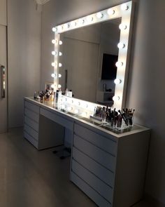 a vanity with lighted lights and makeup on it