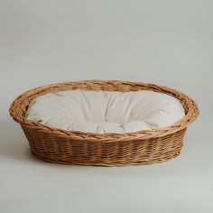 a wicker basket with a white pillow in the center on a grey background,