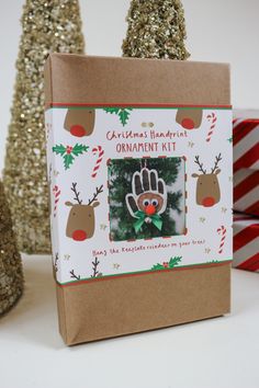 a christmas ornament kit in a gift bag with reindeers and trees around it