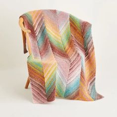 a multicolored blanket sitting on top of a wooden chair