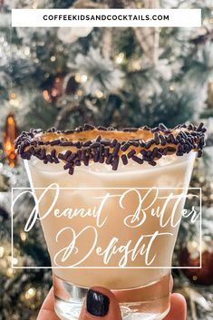 a hand holding a drink in front of a christmas tree with the words, peanut butter dessert