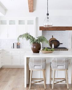 two chairs sitting on top of a white kitchen counter next to a potted plant