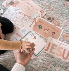 two people sitting on the floor with some paper and magnets in front of them