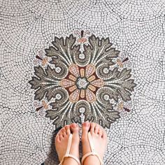 a person standing on the ground with their feet up in front of a mosaic floor