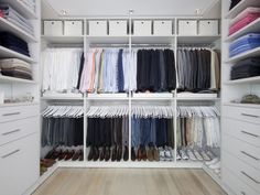 an organized closet with white drawers and shelves filled with folded shirts, pants and shoes