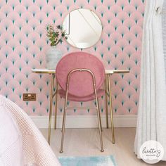 a pink chair sitting in front of a mirror on top of a wooden floor next to a bed