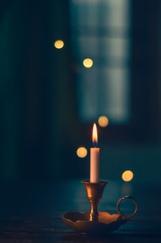 a lit candle sitting on top of a table next to a tea light holder in the dark