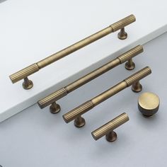 an assortment of brass handles and knobs on a white surface