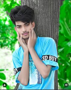 a young man leaning against a tree with his hand on his face