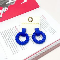 Made to Party Twisted Circle Earrings in Royal Blue. Pictured on an open page of a book. Bold Blue Drop Earrings, Bold Blue Jewelry For Party, Trendy Blue Drop Earrings, Bold Blue Earrings For Gift, Giddy Up Glamour, Earrings Red, Matching Necklaces, Circle Earrings, Ear Piercings