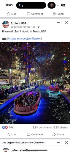 a boat filled with people floating down a river next to a tree covered street at night