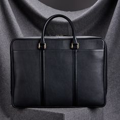 "Slim black leather briefcase for men, crafted from full grain cow hide leather. An ideal choice for daily commute to work and for business travel.  EXTERIOR : The Exterior is made from 100% Genuine Pebble Grain Leather, designed to be unaffected by wear and tear of everyday use. The Top handles are made from 100% Genuine Leather with a Smooth Finish. The Leather used for the Top Handles requires it to be stiff. *Kindly note: For our Briefcase options in Brown leather- the entire product is crafted from full grain cow hide leather in brown, with a smooth finish. This is as shown in the image.  INTERIOR : The interior is made from certified Viscose Fabric. The interior comprises two compartments, one well padded to safely store your Laptops/Tablets, and the other compartment to store all yo Business Briefcase With Top Carry Handle, Classic Black Briefcase With Zipper Closure, Classic Black Briefcase With Zipper, Rectangular Briefcase With Top Carry Handle For Business, Rectangular Business Briefcase With Top Carry Handle, Classic Black Rectangular Laptop Bag, Classic Briefcase With Zipper For Business Trips, Classic Business Laptop Bag Rectangular, Black Formal Laptop Bag With Zipper Closure