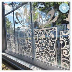 a window with decorative iron work on the outside and inside glass doors that have snowflakes hanging from them