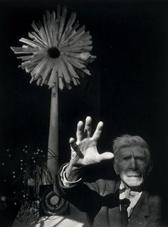 an old man holding his hands up in front of a flower