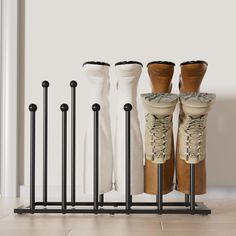 four pairs of boots are lined up in front of a white wall with black poles