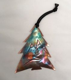 a metal christmas tree ornament hanging on a string