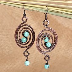 The classic elegance of the Armenian region merges with luminous jewels, bringing an exquisite design to life. Artisans Hasmik and Musheg work long hours with copper to create the spiral accents that compose these dangle earrings, whose antiqued finish is enhanced by reconstituted turquoise stones shining with ethereal and refreshing light. Copper Jewelry Diy, Crazy Jewelry, Wired Jewelry, Work Earrings, Wire Earrings Handmade, Wire Ideas, Wire Jewelry Earrings, Wire Wrap Jewelry Designs, Wrapped Rings