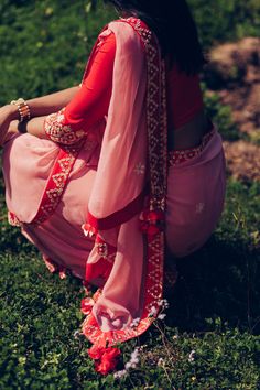 Editor's Note This set features a poppy red blouse with gather detail in the front hand-embroidered sleeves and silk chiffon pyaazi pink saree with poppy red hand emb. border and signature tassels. Color: Pyazi Pink; Poppy Red Fabric: 100% Silk; 100% Silk Georgette Care: Dry Clean Only About the Designer MadSamTinZin brings together the distinctive experiences and talents of four young designers through a uniquely collaborative design process that is all about their love for quality and craftsma