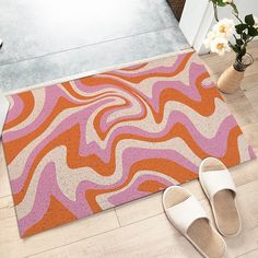 a pair of slippers sitting on the floor next to an orange and pink rug