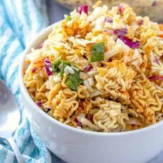 a white bowl filled with noodles and vegetables on top of a blue towel next to a pot