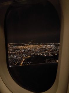 an airplane window looking out at the city lights