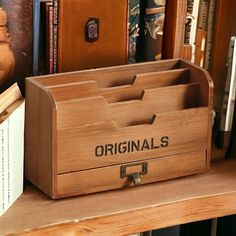 a wooden box with the word original's written on it sitting on a book shelf